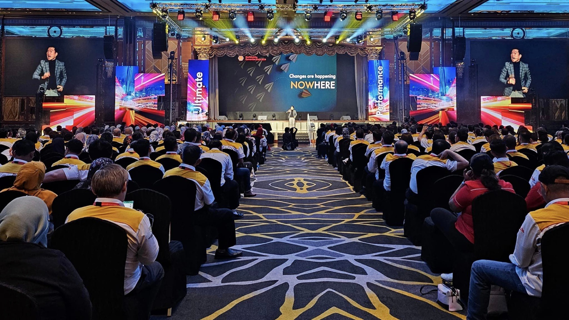 Wesley Chan delivering a keynote to a packed audience in a ballroom venue